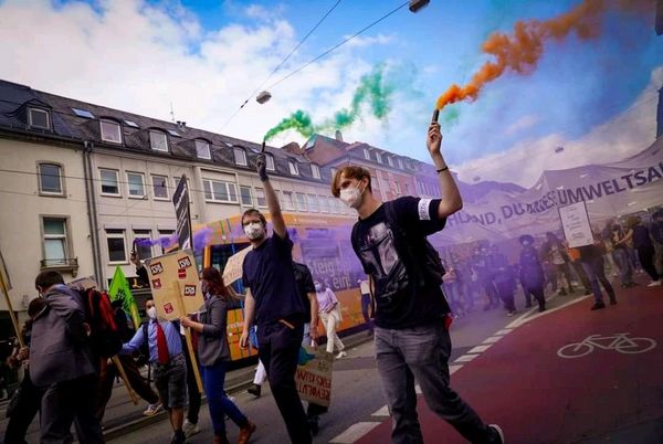 Bild von einer Demo, bei der mehrere Menschen Rauchtöpfe hochhalten