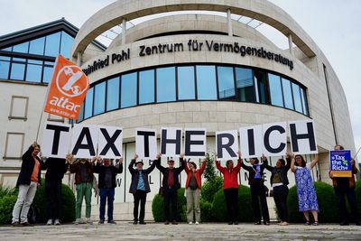 Vor dem "Reinhold Pohl Zentrum für Vermögensberatung" stehen Aktivist*innen die A1-große Buchstaben hochhalten, die den Slogan "Tax the Rich" ergeben