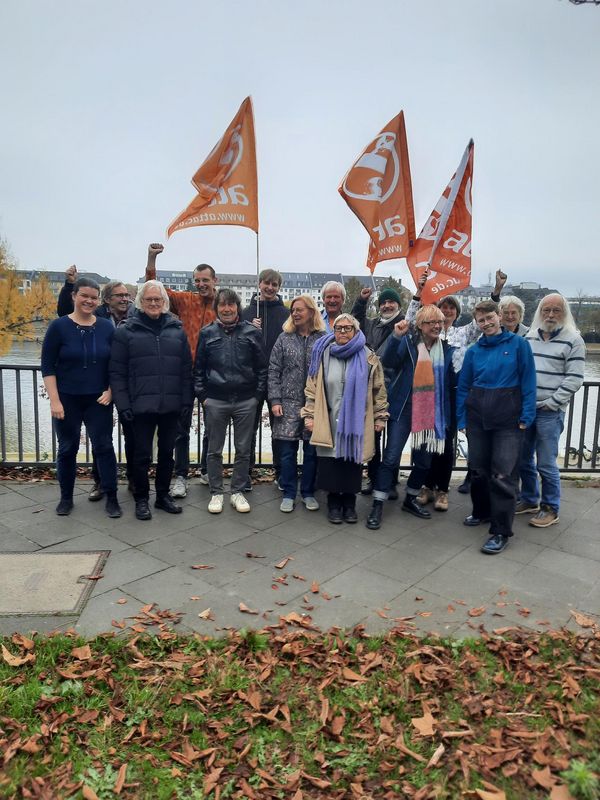 Ein Gruppentreffen der Ratsmitglieder mit Fahnen vor einem Fluss