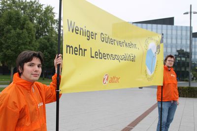 Zwei Aktivist*innen, halten ein Banner mit dem Text "Weniger Güterverkehr – mehr Lebensqualität"