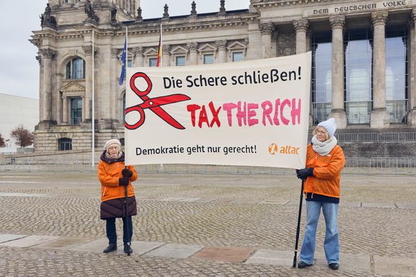 Zwei Attacis halten ein Banner mit dem Text "Die Schere schließen. Tax the Rich. Demokratie geht nur gerecht"