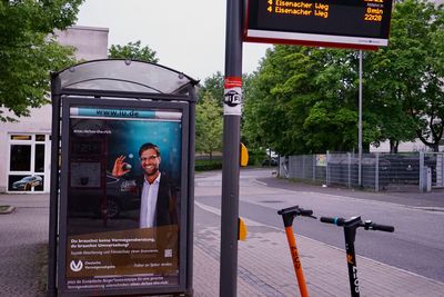 Blick auf eine Bushaltestelle, bei der das Werbeplakat gegen ein Fake-Plakat ausgetauscht wurde. Auf ihm ist Jürgen Klopp bei einer umgestalteten Werbung der Deutschen Vermögensberatung AG zu sehen und der für die Europäische Bürger*inneninitative "Tax the richt wirbt"